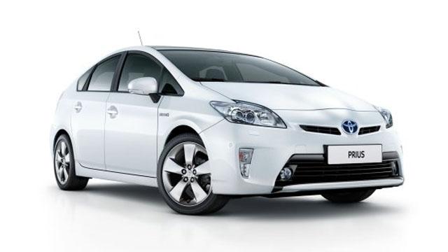 En hvit Toyota Prius med moderne design og aerodynamiske linjer, parkert på en lys bakgrunn.
