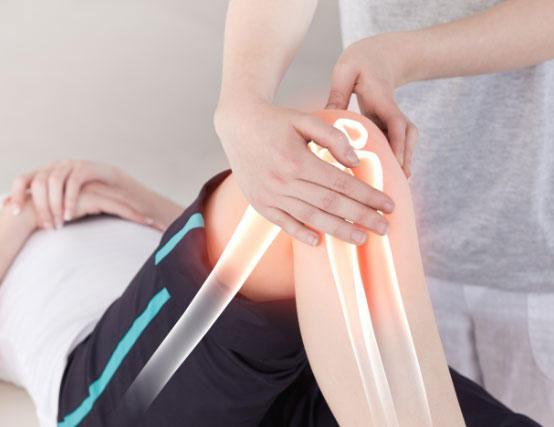En fysioterapeut utfører behandling på et knær med fokus på leddbevegelse og rehabilitering.