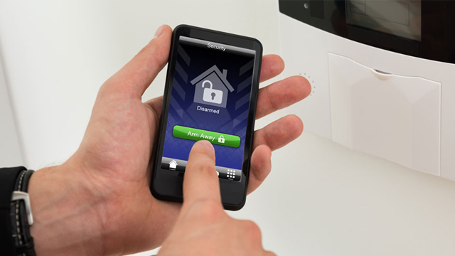 En hånd som bruker en smarttelefon med en app for å låse opp et smart hjem-system.