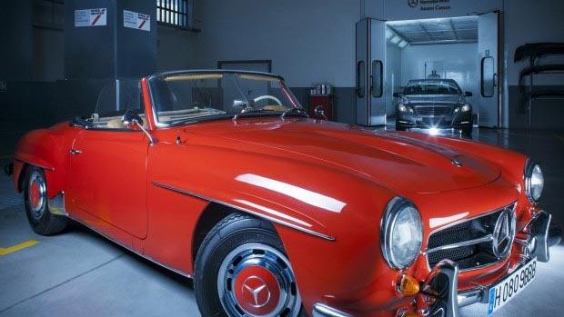 En rød Mercedes-Benz sportsbil fra 1950-tallet står i et verksted med en annen bil i bakgrunnen.