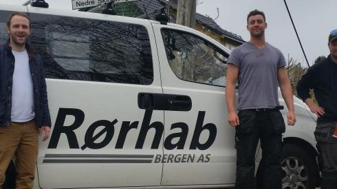 Tre menn står foran en varebil med teksten "Rørhab Bergen AS" på siden.
