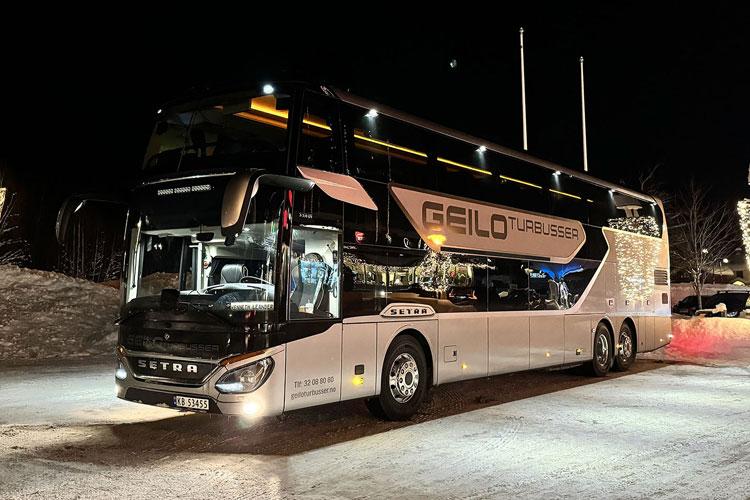 En moderne dobbeldekkerbuss parkert om natten med lys i Geilo, Norge.