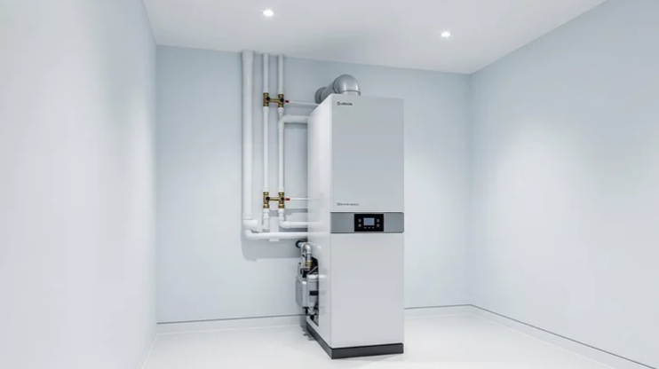 En moderne varmepumpe med rørinstallasjon i et lyst rom med hvite vegger.