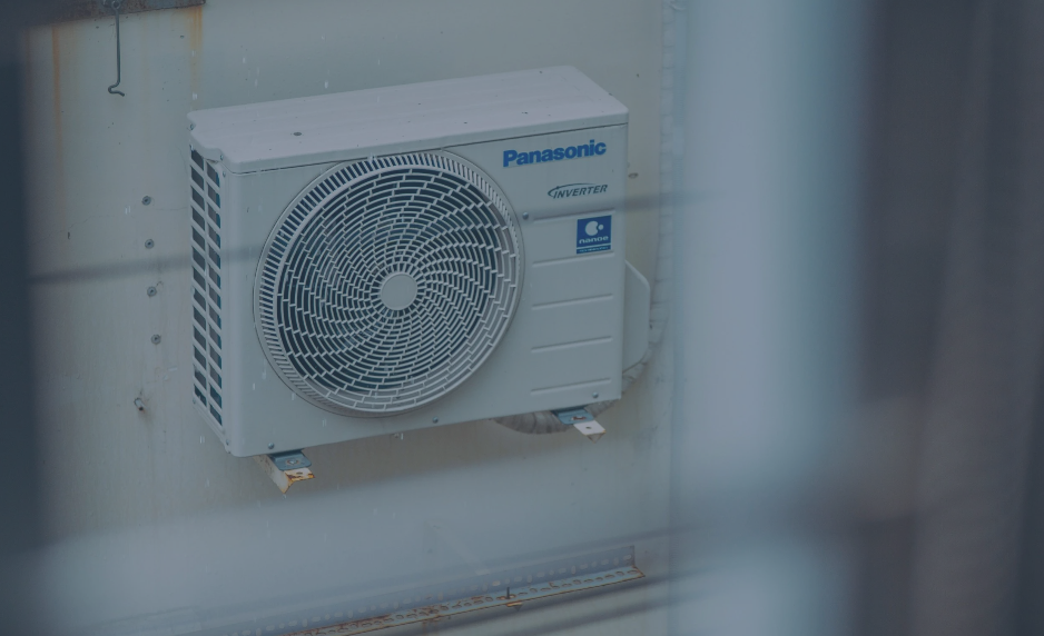 Utendørs Panasonic klimaanlegg montert på veggen, med synlig vifte og kjøleenhet.