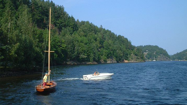 To båter seiler på en rolig innsjø omkranset av frodig grønn skog.
