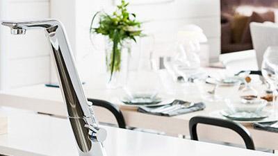 Kjøkkenkran i moderne design med en elegant borddekkning i bakgrunnen.