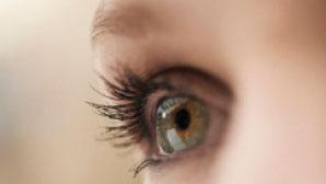 Nærbilde av et menneskelig øye med lange øyevipper og grønnbrune iris.