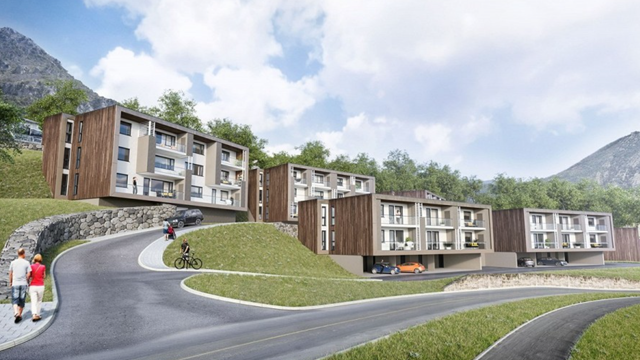 Moderne leilighetsbygg med tre og stein, beliggende ved en svingete vei i naturskjønt landskap.