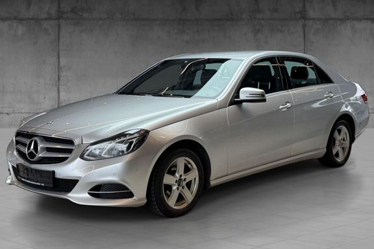 En sølvfarget Mercedes-Benz E-klasse sedan stående på en grå bakgrunn.