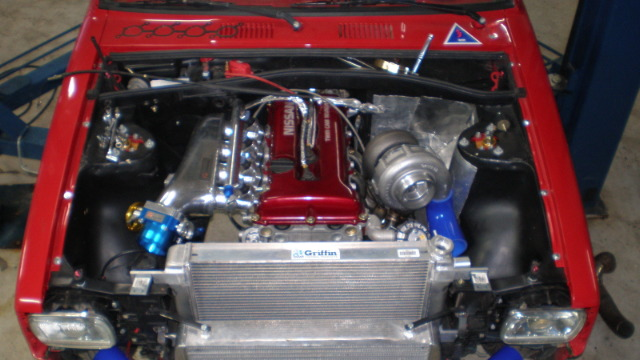 Bilde av en rød bilmotor med turbolader, intercooler og detaljerte motorkomponenter.