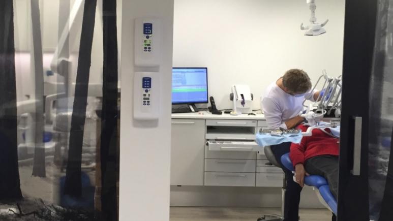 Tannlege som behandler en pasient i et moderne tannlegekontor med datamaskin og utstyr.