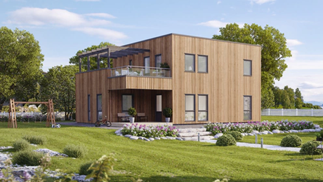 Moderne trehus med balkong, plassert i en grønn hage med blomster og trær i bakgrunnen.