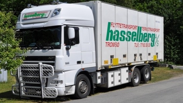 En hvit lastebil fra Hasselberg med påskrift om flytte- og transporttjenester, parkert langs veien.