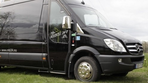 En svart Mercedes varebil parkert på gresset, med logoen til et transportfirma synlig på siden.