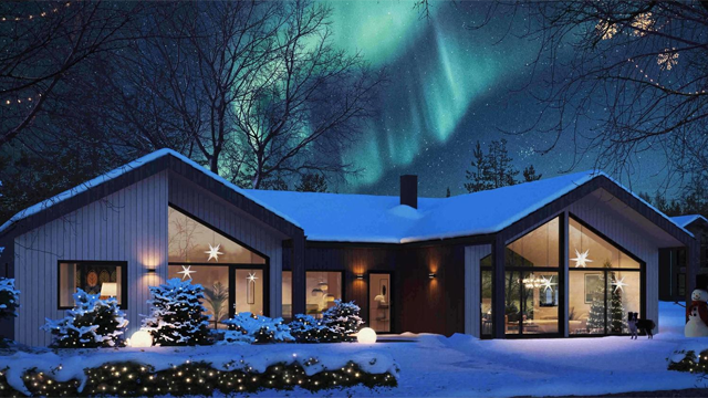 Moderne hus dekket av snø med nordlys på nattehimmelen og julelys i hagen.