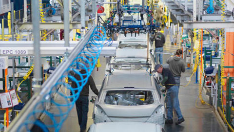 Bilproduksjon i en fabrikk med arbeidere som jobber med bilkarosserier og produksjonsutstyr.