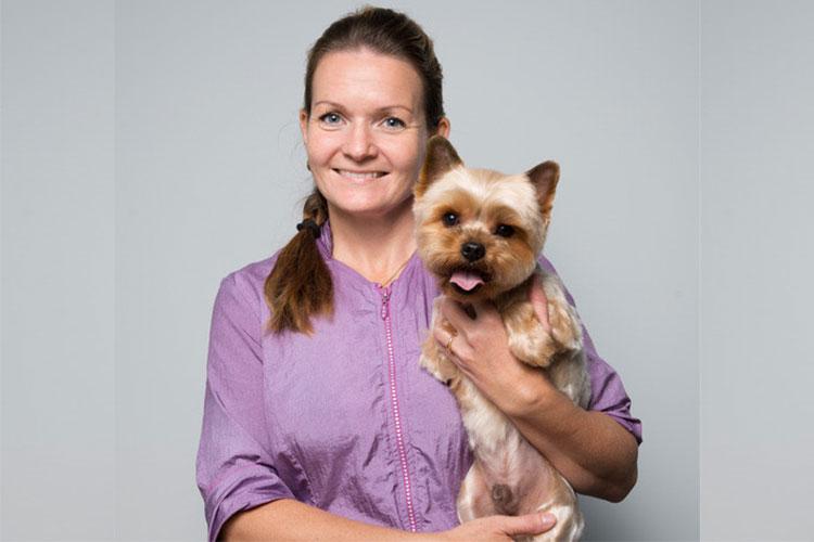 Kvinne holder en liten Yorkshire Terrier med en glad uttrykk i studio.