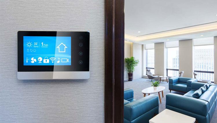 Moderne termostat på veggen i et stilrent rom med blå sofaer og bord.