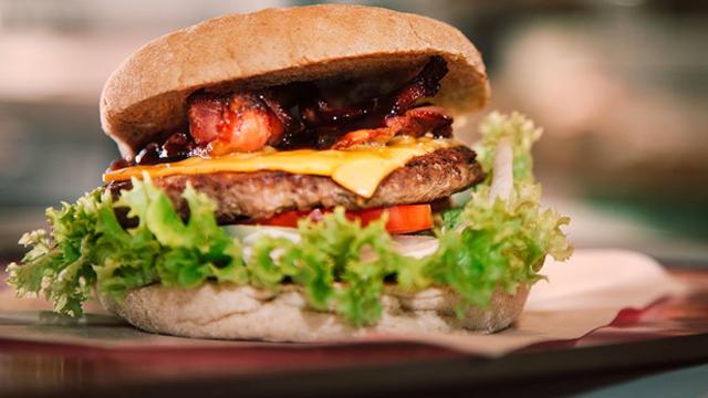 Saftig hamburger med ost, bacon, salat og tomat i et grovt brød.