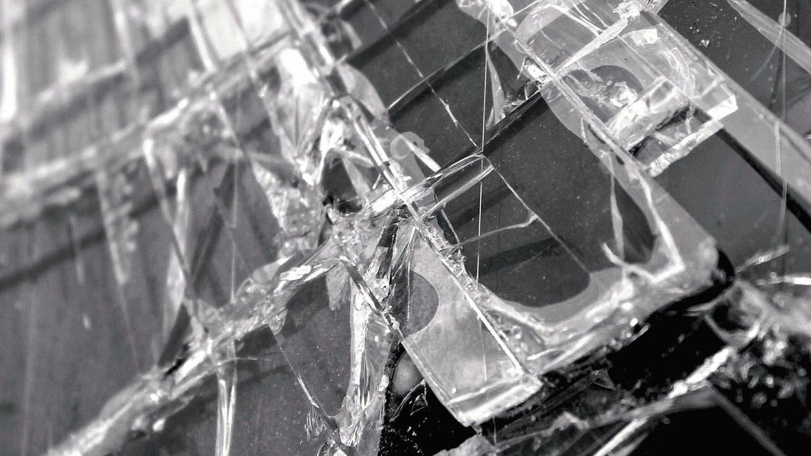 Et nærbilde av knust glass med skarpe kanter og reflekterende overflater.