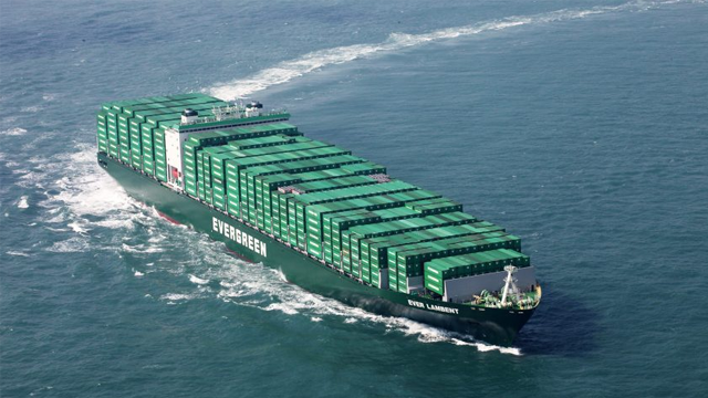 Et stort containerskip med grønne containere seiler gjennom havet.