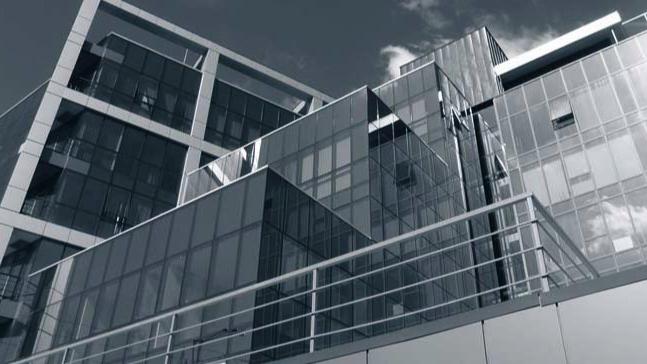 Moderne kontorbygg med glassfasader og geometrisk design under en klar himmel.