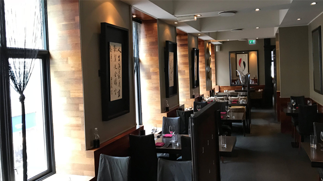 Moderne restaurantinteriør med trevegger, borddekorasjoner og kunstverk på veggene.