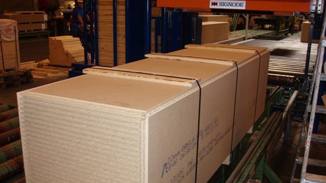 Stable med pakket sponplater på en produksjonslinje i en fabrikk.