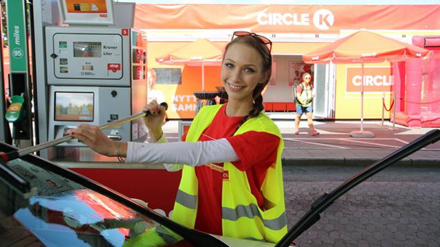 Kvinne i gul vest fyller drivstoff på en bil ved en Circle K bensinstasjon.
