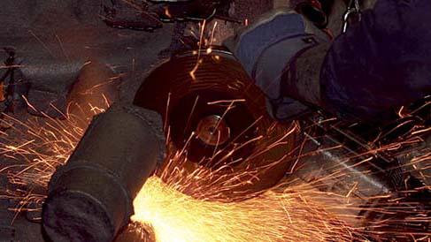 En person bruker en vinkelsliper som skaper gnister under metallbearbeiding.