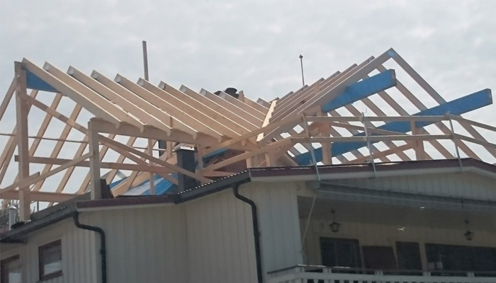 Takramme av treverk på et hus under konstruksjon, med blå beskyttelsesplater.