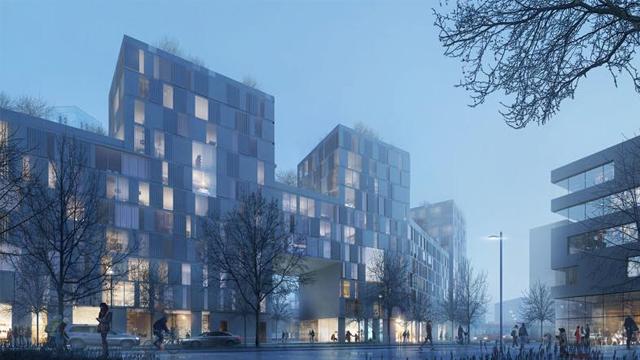 Moderne bygninger i en bygate, opplyst i skumringen med trær og mennesker i bevegelse.