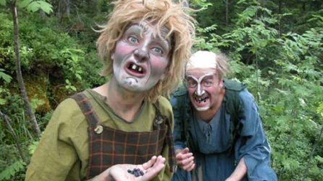 To personer med skremmende ansiktsmaling som står i en skog, en av dem holder en håndfull bær.