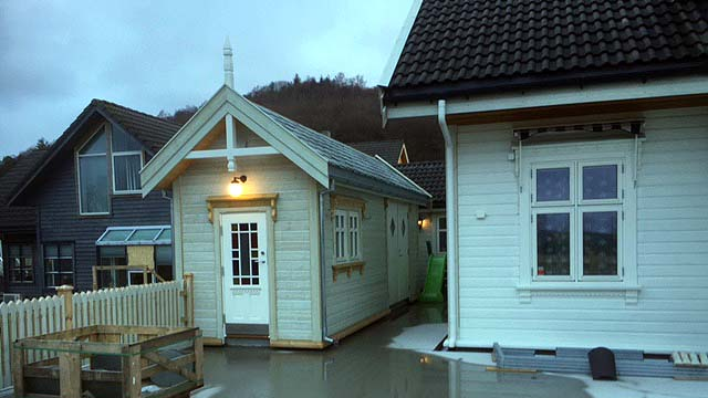Moderne hus med hvit fasade og takstein, plassert i et boligområde med flere bygninger.