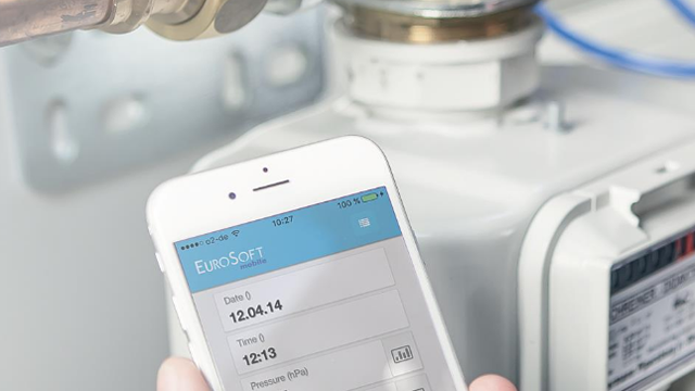 En hånd som holder en smarttelefon med en app som viser data fra en gassmåler.