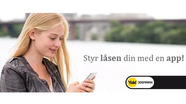 Ung kvinne med langt, lyst hår som bruker en smarttelefon ved vannet, med en bro i bakgrunnen.