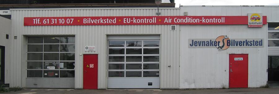 Bilverksted med rød inngang og skilt for bilservice, EU-kontroll og klimaanleggskontroll.