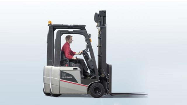 En mann kjører en Nissan gaffeltruck med en løftemast i en lys bakgrunn.