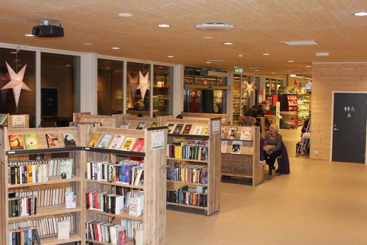 Moderne bibliotek med tre bokhyller, lesesoner og stjerner i taket, skaper en koselig atmosfære for besøkende.