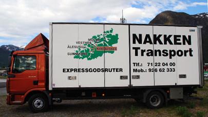 Lastebil med NAKKEN Transport-logo og kontaktinformasjon, stående i et naturskjønt område med fjell.