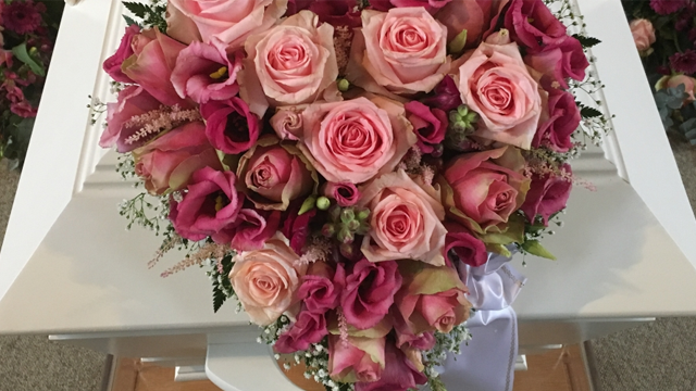 En vakker bukett med rosa roser og lisianthus, plassert på en hvit kiste.