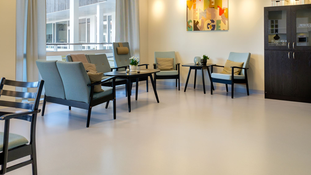 Lyst oppholdsrom med moderne møbler, stoler, bord og kunstverk på veggen.