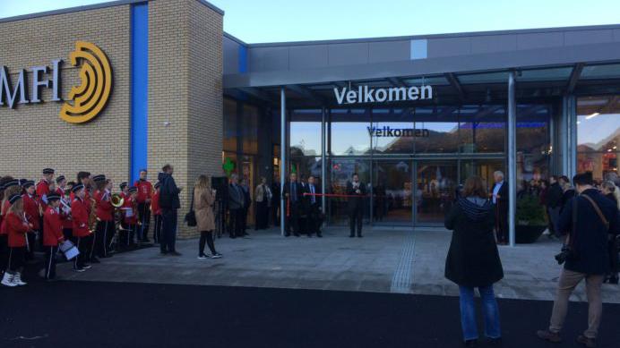 En gruppe mennesker står foran inngangen til MFI-bygningen, med en velkomstplakat og feststemning.