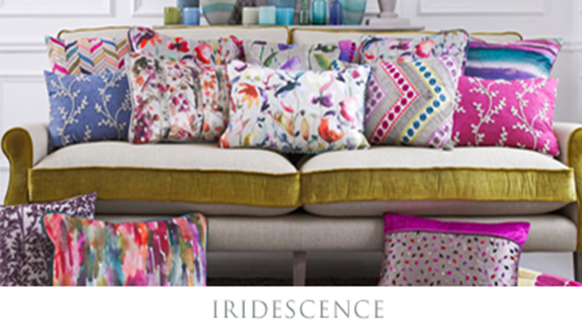 En sofa med fargerike puter i forskjellige mønstre og farger, inkludert blomster og geometriske design.