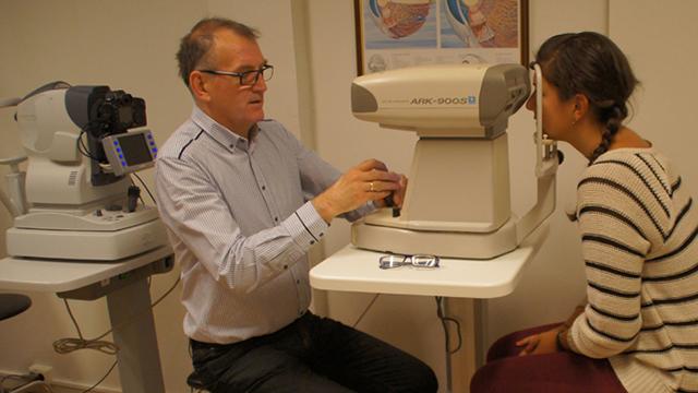 En optiker undersøker en pasient med en synstestmaskin i et moderne øyelegesenter.