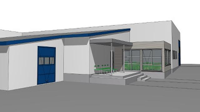 Moderne bygning med blå detaljer, inngangsparti og vinduer, omgitt av et asfaltert område.