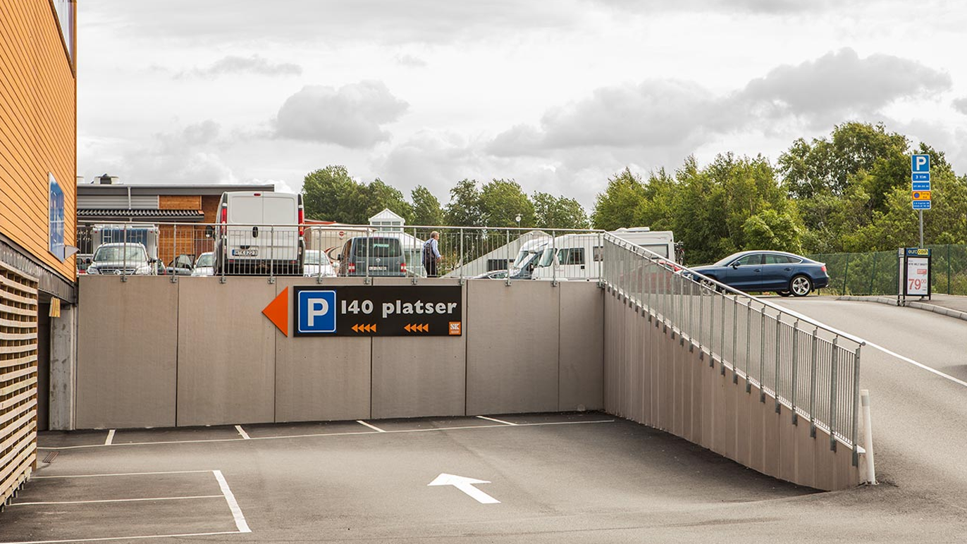 Parkeringshus med skilt som viser 140 plasser og en vei som fører ned til parkeringsområdet.