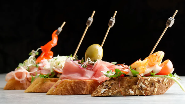 Lekkert smørbrød med reker, skinke, oliven og grønnsaker på grovt brød, dekorert med spyd.