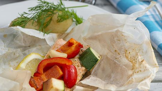Laks med grønnsaker som paprika, squash og sitron, pakket i papir, servert med potet og dill.