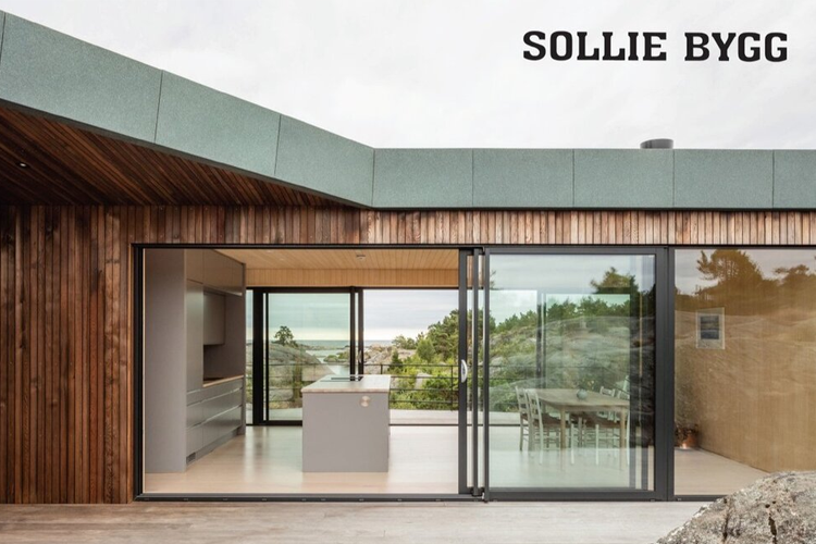 Moderne hus med store vinduer, åpen stue og kjøkken, utsikt mot havet og naturlige omgivelser.